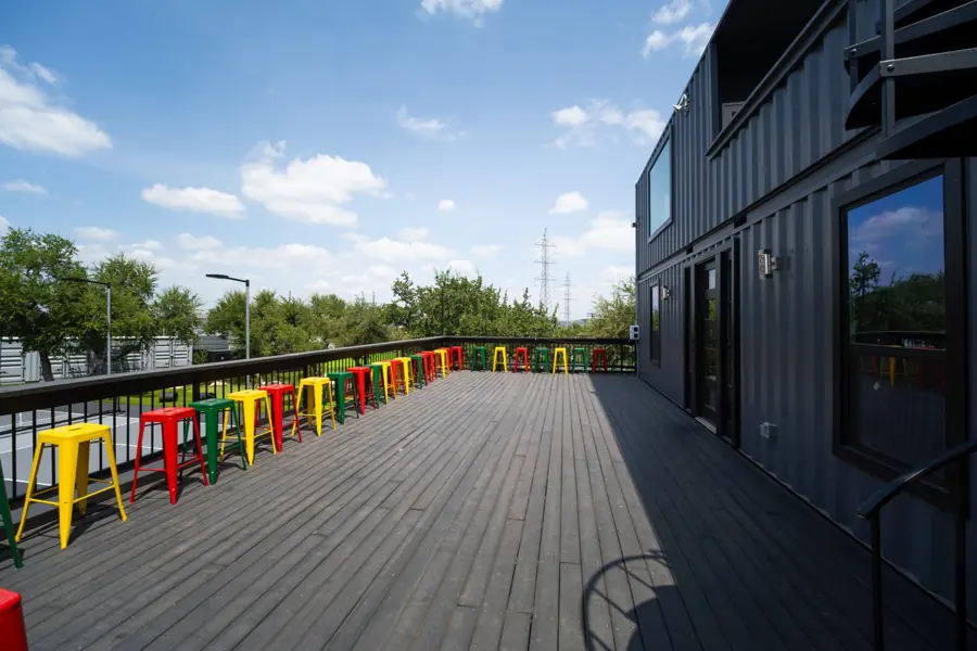Second-floor deck with a row of colorful bar stools