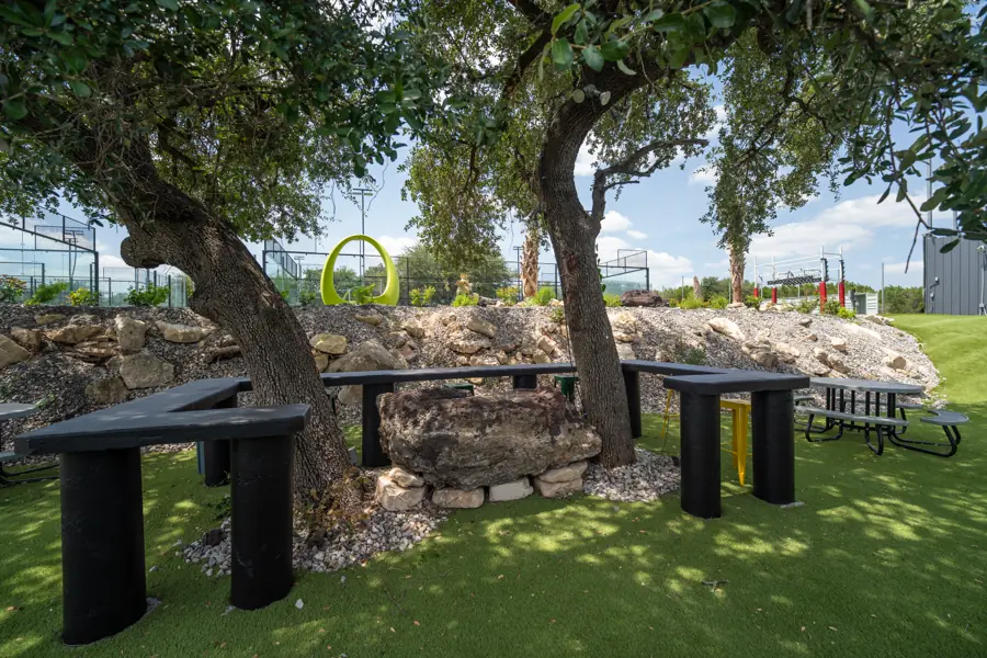 Shaded picnic tables among oak trees and limestone boulders