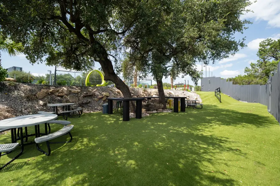 Picnic tables in the shade of oak trees beside the turf